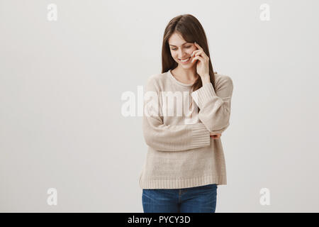 Vous me faire rougir. Studio shot of woman friendly timide dans les tenues à la recherche vers le bas avec le sourire joyeux et en maintenant les doigts sur le visage, en marchant avec son chien dans le parc, avec la gentillesse Banque D'Images