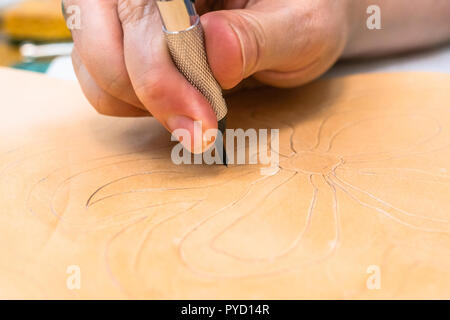 Atelier de la Sac en cuir sculpté - artisan sculpte l'ornement sur la surface du cuir tanné de légumes bruts par couteau pivotant Banque D'Images