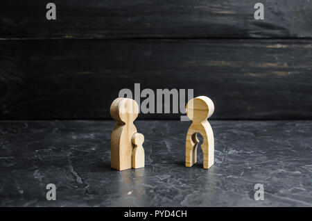 Figurine en bois d'une mère et d'un vide dans la forme d'un enfant regarde avec envie la mère avec l'enfant. Notion de futilité, le désir d'avoir Banque D'Images