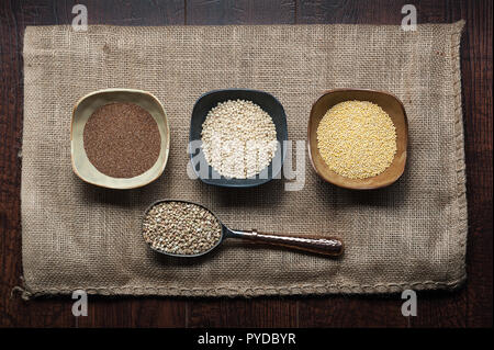 Grains anciens de teff, le sorgho, le millet et le sarrasin dans des bols et d'un scoop sur un sac de jute. Banque D'Images