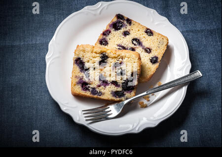 Deux tranches de pain thé aux bleuets et sur une assiette avec une fourchette et le fond bleu. Banque D'Images