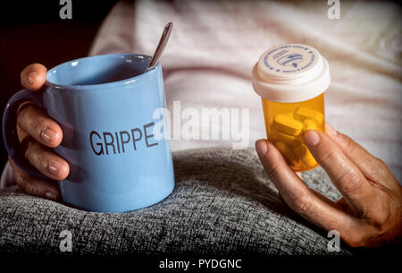 Woman examining médicament traitement, plusieurs bateaux dans la main, se tasse infusion avec blue Cup written grippe, concept de la maladie Banque D'Images