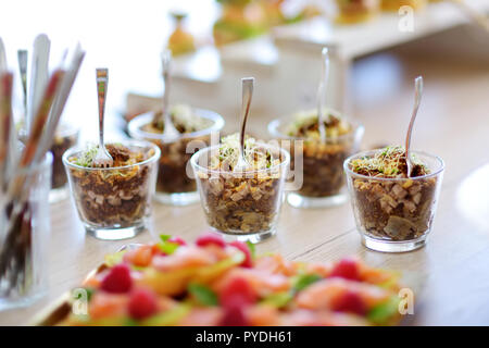 Fraîche et délicieuse salade de légumes et de porc servi dans un mini-verres sur une partie ou la réception de mariage. Les plaques avec un assortiment fantaisie finger food snacks sur Banque D'Images