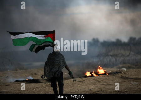 Manifestant palestinien vu tenant un drapeau et un lance-pierres lors des affrontements, à la suite d'une manifestation près de la frontière avec Israël. Banque D'Images