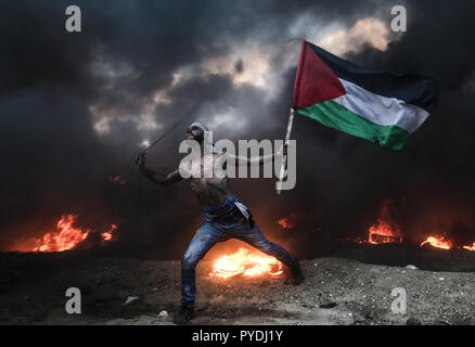 Manifestant palestinien vu tenant un drapeau lors de l'utilisation d'un lance-pierre pour lancer des pierres lors des affrontements à la suite d'une manifestation près de la frontière avec Israël. Banque D'Images