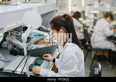 Une femelle technicien vérifie un conseil de l'ordinateur dans une usine. L'occupation professionnelle. Spécialiste hautement qualifié dans le domaine de l'assemblage d'ordinateurs o Banque D'Images