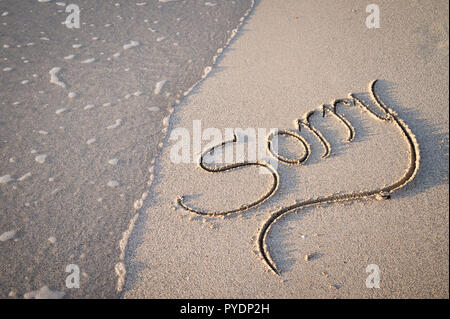 Désolé message écrits en lettrage calligraphie sur plage de sable lisse Banque D'Images