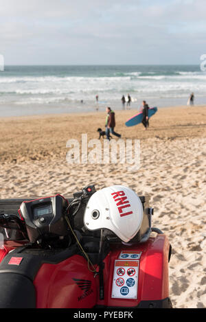 Un casque de sécurité de la RNLI sur le guidon d'un quad garé sur la plage de Fistral à Newquay en Cornouailles. Banque D'Images