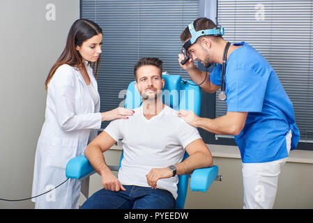 Un beau médecin avec une charmante assistante à examiner le patient dans la chambre d'hôpital. Banque D'Images