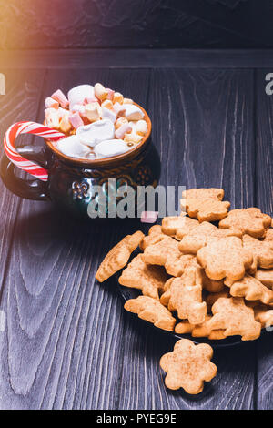 Guimauves avec tasse en céramique et des bonbons de Noël à côté d'un bol plein de cookies biscuit Banque D'Images