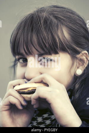 Happy teen girl eating a burger Banque D'Images