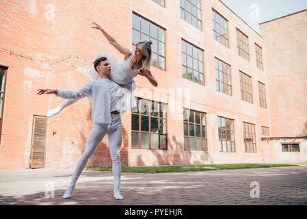 Les jeunes danseurs de ballet dans des vêtements blancs dansant sur urban city street Banque D'Images