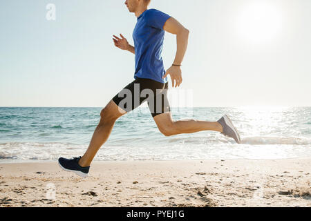 Homme runner le long de plage dans la lumière du soleil Banque D'Images