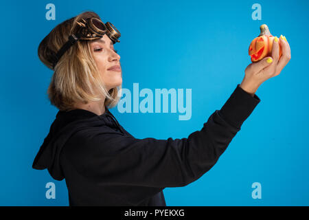 Portrait of Girl goth punk à vapeur verres à la confiance dans un orange citrouille sculptée. Thème de l'Halloween holiday shoot Banque D'Images