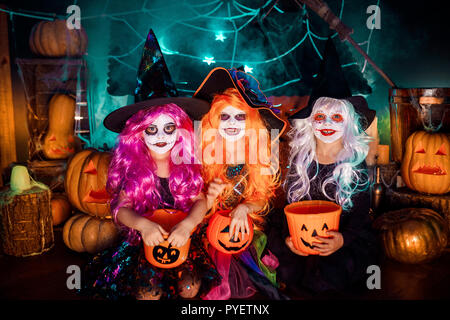 Trois belles filles dans un costume de sorcière. Funny sœurs célèbrent la maison de vacances. Jolly enfants en costumes de carnaval prêt pour l'Halloween dans halloween decorations Banque D'Images