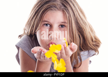 Young caucasian girl blowing pétales jaunes au spectateur pour rire, l'amour ou le plaisir de célébrer le printemps Banque D'Images