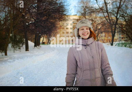 Une jeune fille ukrainienne au cours d'une balade dans un parc en hiver avec un large sourire sincère. Banque D'Images