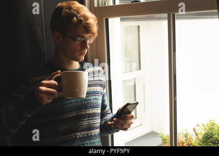 L'homme à l'aide de téléphone mobile alors que le café Banque D'Images