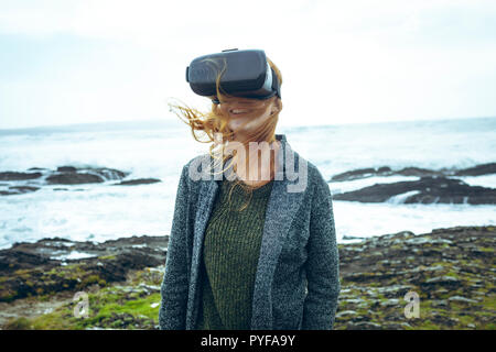 Femme à l'aide de casque de réalité virtuelle dans la plage Banque D'Images