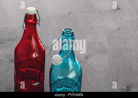 Bouteilles colorées, bleu et rouge avec un bouchon en verre crantée sur le cou, sur une table en bois. Banque D'Images