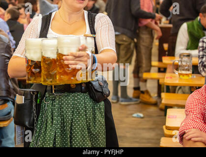 L'Oktoberfest, Munich, Allemagne. Femme garçon avec costume traditionnel holding beers Banque D'Images