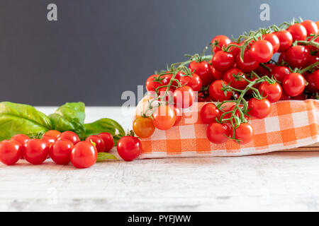 Tomates cerise sur la vigne avec des feuilles de basilic Banque D'Images