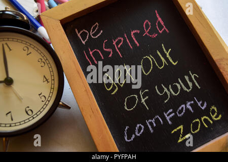 S'inspirer de sortir de votre zone de confort expression manuscrite colorés sur tableau, réveil avec motivation et concepts d'éducation Banque D'Images