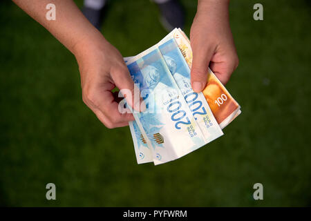 Femme tenant un tas de billets Nouveau shekel israélien dans ses mains Banque D'Images