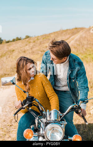 Jeune couple assis sur moto et smiling at each other Banque D'Images