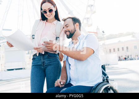 À l'aide de voyageurs souriant et smartphone site sur street Banque D'Images