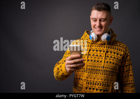 Happy man wearing hoodie et écouteurs en utilisant le téléphone mobile Banque D'Images