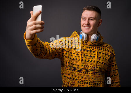 Sweat homme portant un casque et tout en tenant avec téléphone selfies Banque D'Images