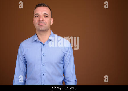 Businessman wearing blue shirt contre fond brun Banque D'Images