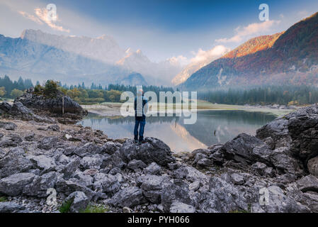 Homme debout active sur la roche à la recherche de paysages alpins. Banque D'Images