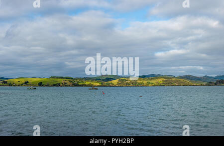 Vue sur la mer avec un patch de la lumière du soleil frappe une prairie avec quelques bateaux de pêche dans l'avant-plan Banque D'Images