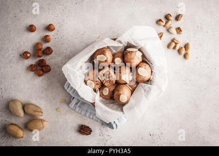 Cacao et noix vegan balles brutes dans un bol de noix de coco sur fond blanc, vue du dessus. Concept alimentaire à base de plantes. Banque D'Images