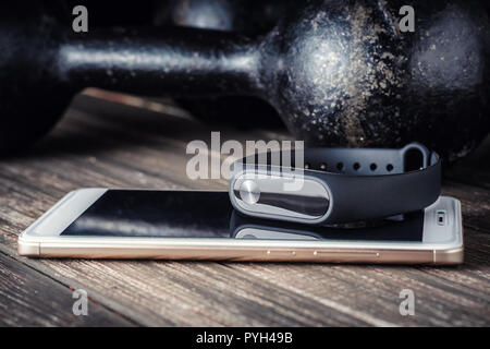 Suivi de remise en forme, smartphone et fer à repasser les haltères sur fond de bois Banque D'Images