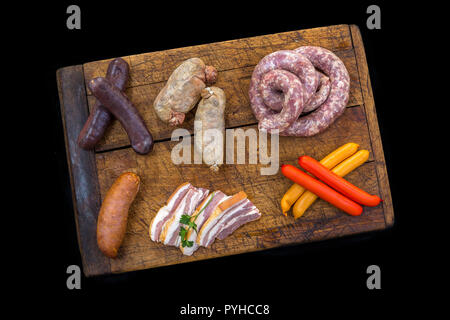 Sélection de crus Français saucisse avec parsleyon,sur une planche en bois noir l'arrière-plan. Banque D'Images