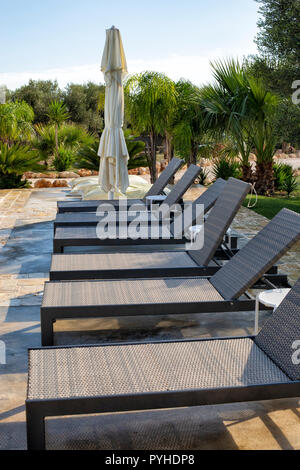 Chaises longues et parasol moderne près de la piscine. Banque D'Images