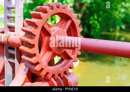 Close-up of a red metal gear sur la vanne. Mécanisme d'ouverture du barrage. Vieille roue dentée sur la rivière. Transfert à l'ouverture du barrage. Vieux cogw Banque D'Images