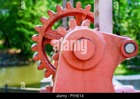 Close-up of a red metal gear sur la vanne. Mécanisme d'ouverture du barrage. Vieille roue dentée sur la rivière. Transfert à l'ouverture du barrage. Vieux cogw Banque D'Images