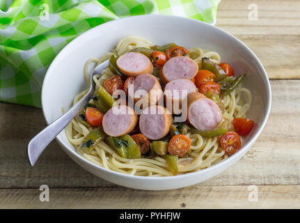 Les pâtes - Spaghetti saucisse avec des tranches de saucisse fumée continental avec des tomates cerise et poivre vert Banque D'Images