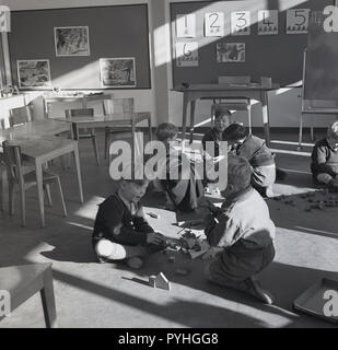 Années 1950, les enfants qui jouent ensemble à l'intérieur sur le sol lors d'une conférence préparatoire à l'école ou la garderie, England, UK. Banque D'Images