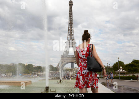 Paris, Ile-de-France, France - une femme avec une robe rouge et blanche à la fontaine dans les Jardins du Trocadéro avec la Tour Eiffel en arrière-plan. Banque D'Images