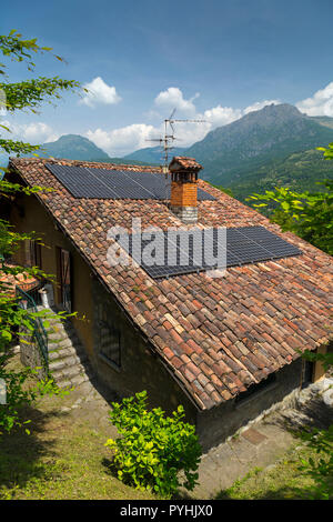 Panneaux solaires et pot de cheminée sur le toit d'un vieux cottage italien (1931-1987). Banque D'Images