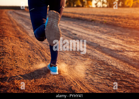 Femme d'exécution dans le champ d'automne au coucher du soleil. Concept de vie sain. Sportifs actifs. Close up de jambes