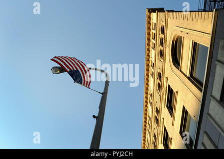 Un drapeau américain est suspendu la tête en bas d'un poteau d'éclairage sur une rue de la ville. Banque D'Images