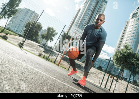 Heureux homme actif à jouer sur le terrain de basket-ball Banque D'Images