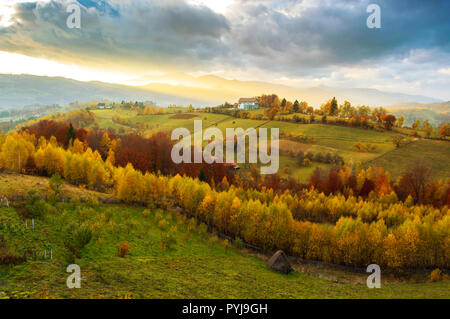 Les collines et montagnes baignées de lumière au coucher du soleil chaud de Poiana Marului, Roumanie. Automne paysage coucher de soleil magique Banque D'Images