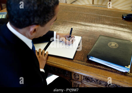 Le président Barack Obama écrit à son bureau dans le bureau ovale 3/3/09. Banque D'Images